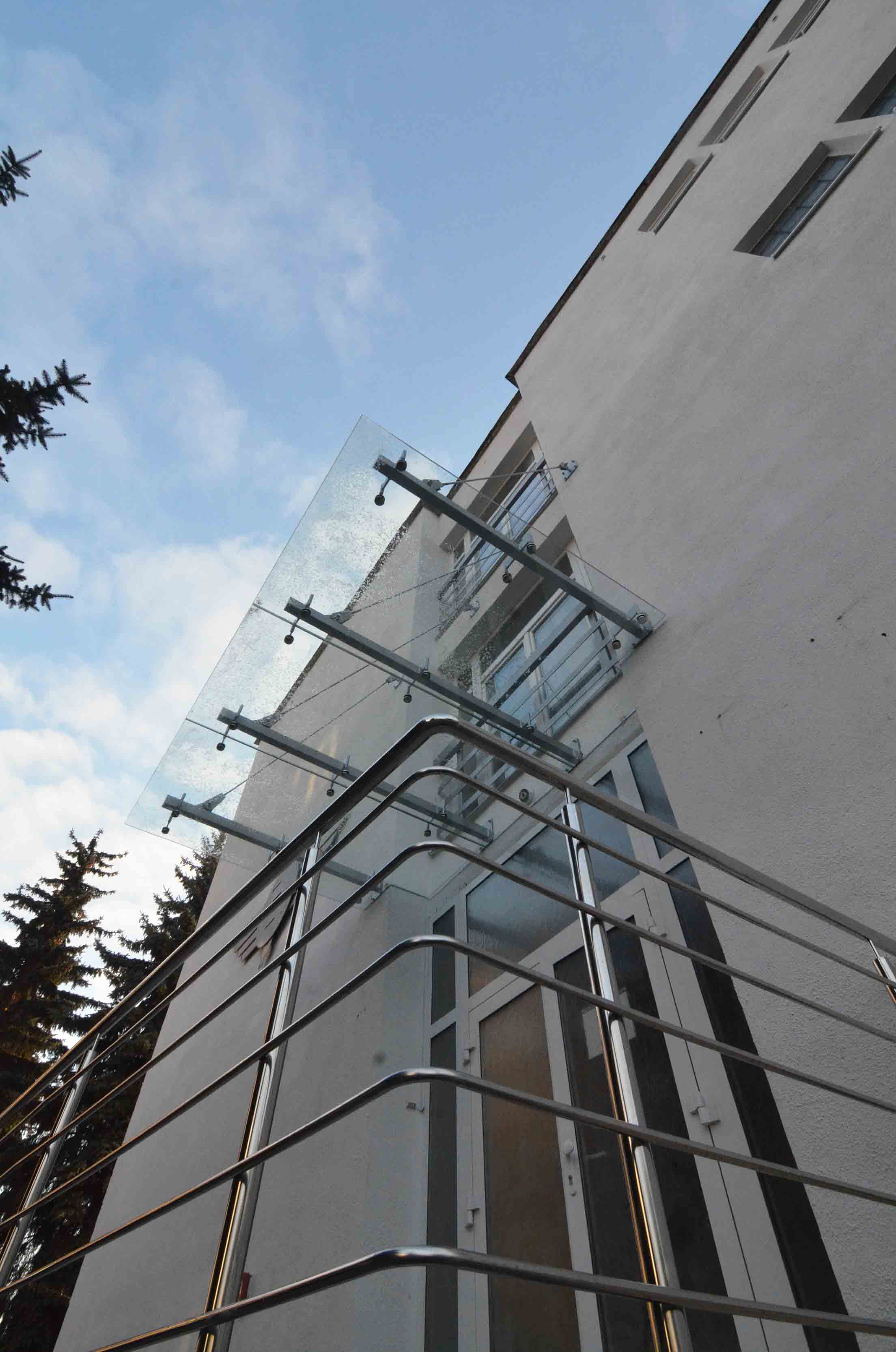 Sklenená markíza s nerezovou konštrukciou zladená s nerezovým zábradlím pred vstupom do budovy | DOMO GLASS
